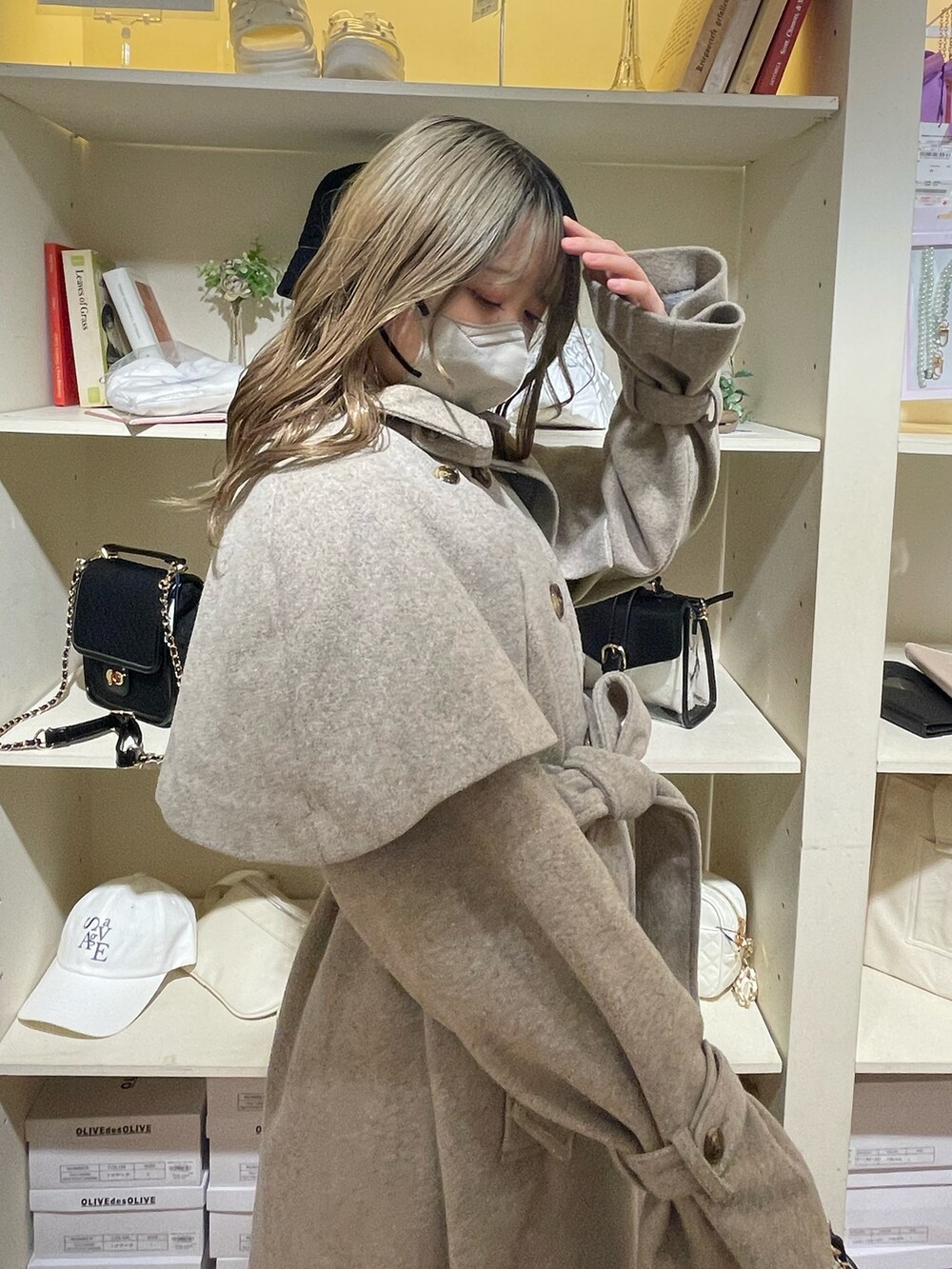 ブラウン系のステンカラーコート、ホワイト系のスニーカー、ホワイト系のショルダーバッグを着用したレディースの夏コーディネートの4枚目の写真