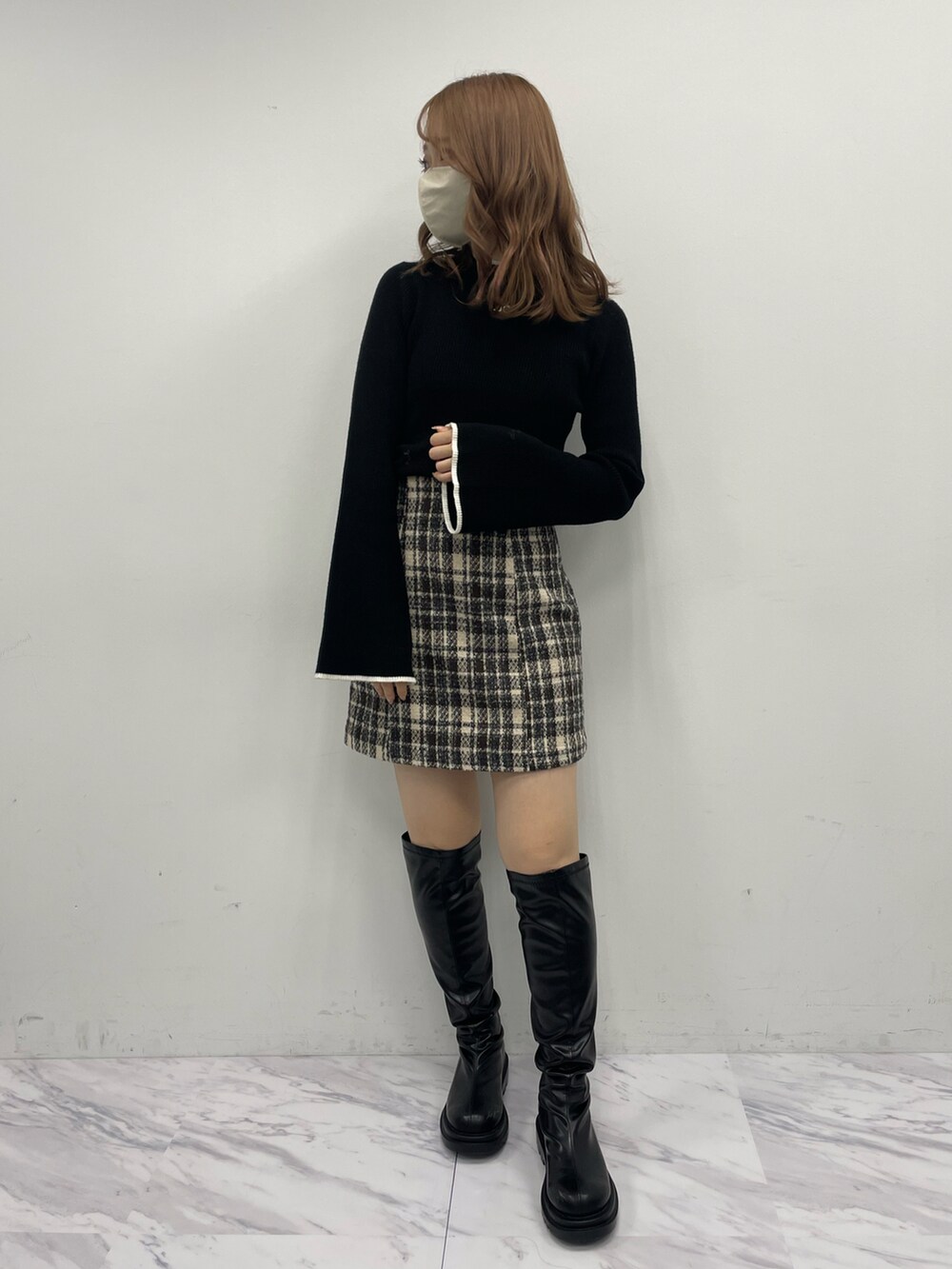ベージュ系のスカート、ブラック系のニット/セーター、ブラック系のブーツを着用したレディースの秋コーディネートの2枚目の写真