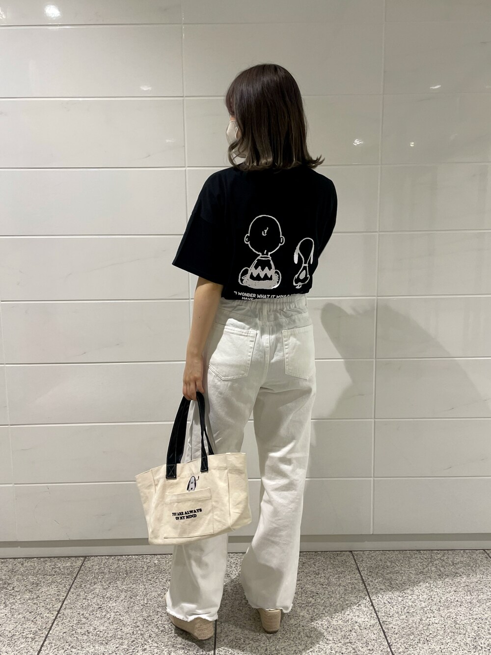 ホワイト系のトートバッグ、ブラック系のTシャツ/カットソー、ホワイト系のデニムパンツを着用したレディースの春コーディネートの2枚目の写真