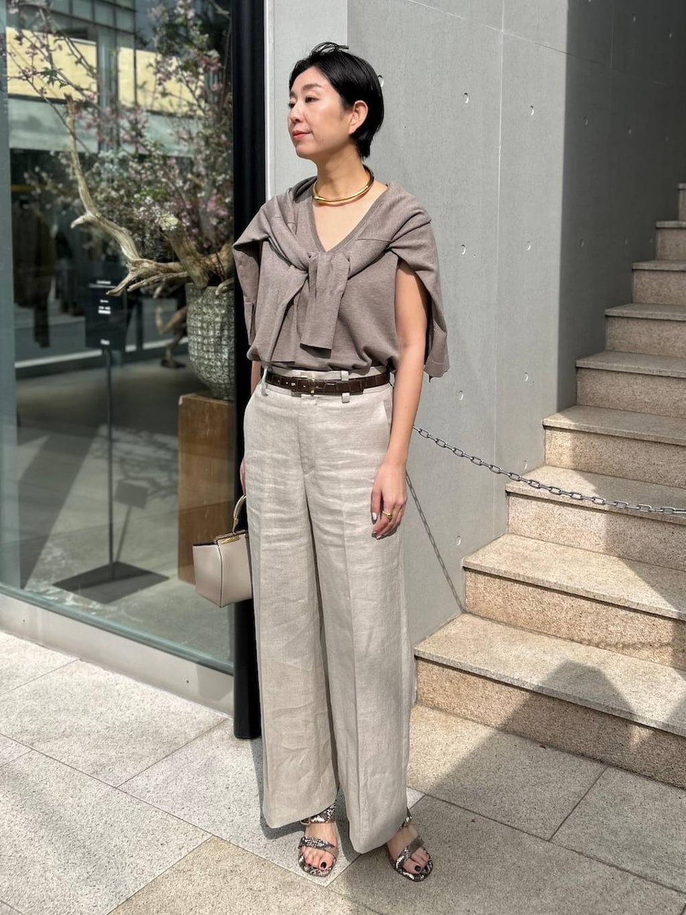 ホワイト系のスラックス、ブラウン系のニット/セーター、ブラウン系のカーディガン/ボレロを着用したレディースの春コーディネートの2枚目の写真