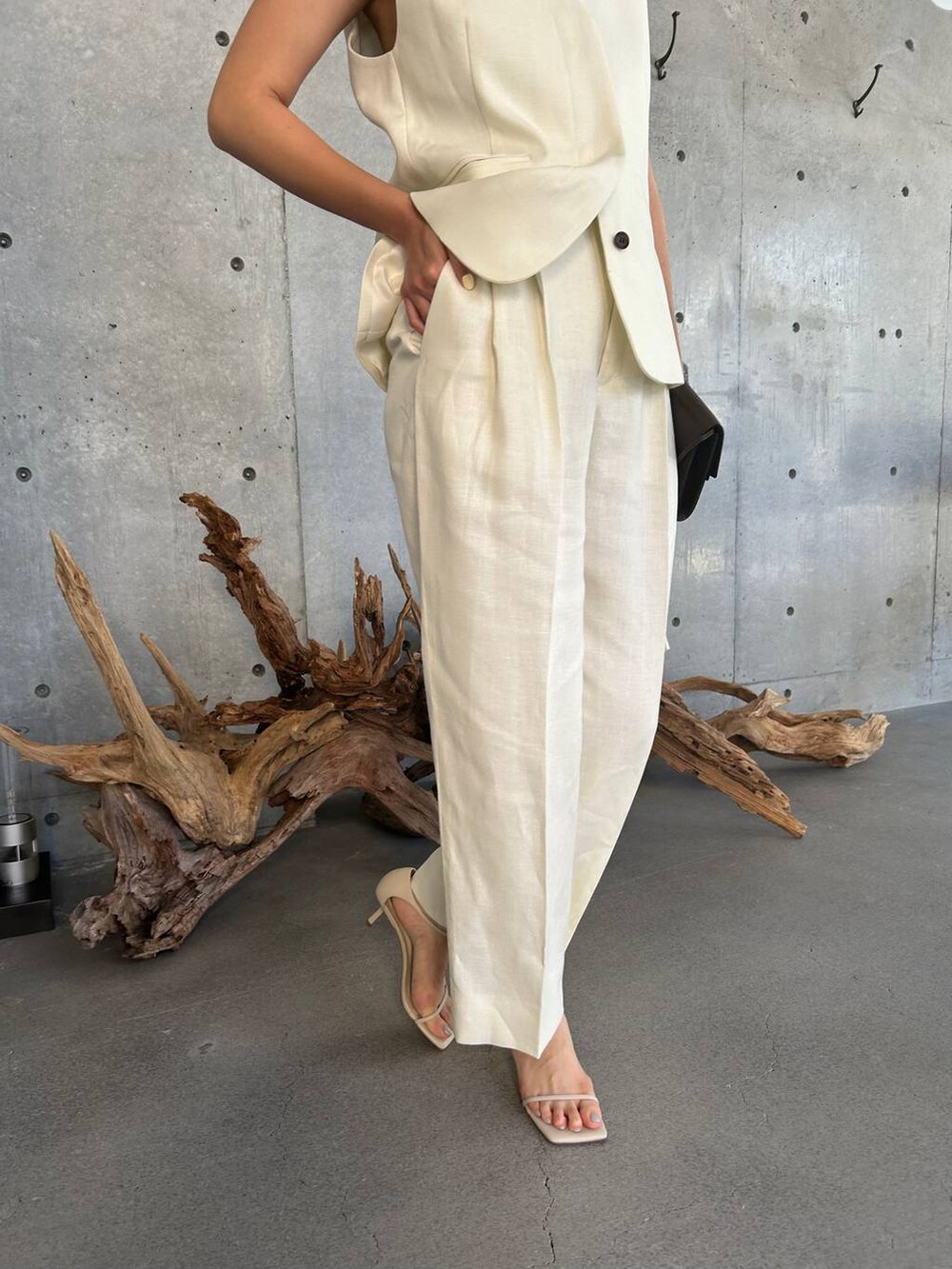 ブルー系のキャミソール、ベージュ系のサンダル、ホワイト系のスラックスを着用したレディースの夏コーディネートの7枚目の写真