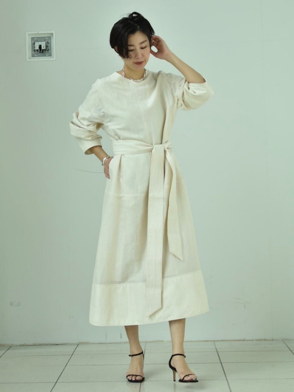 ホワイト系のワンピース、ブラック系のサンダル、シルバー系のネックレスを着用したレディースの春コーディネートの2枚目の写真