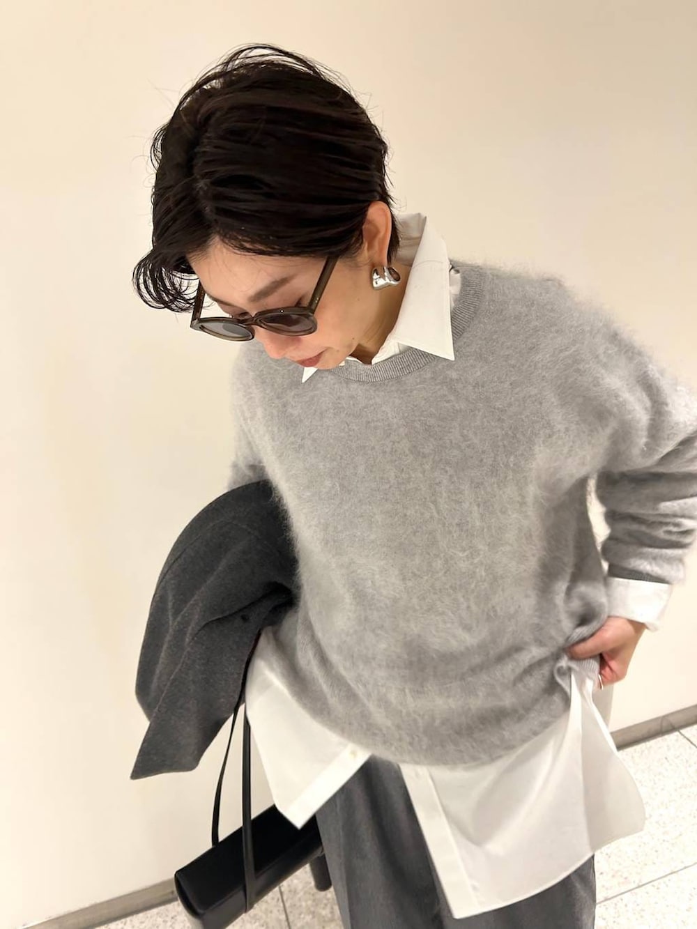 グレー系のニット/セーター、ホワイト系のシャツ/ブラウス、グレー系のスラックスを着用したレディースの秋コーディネートの6枚目の写真