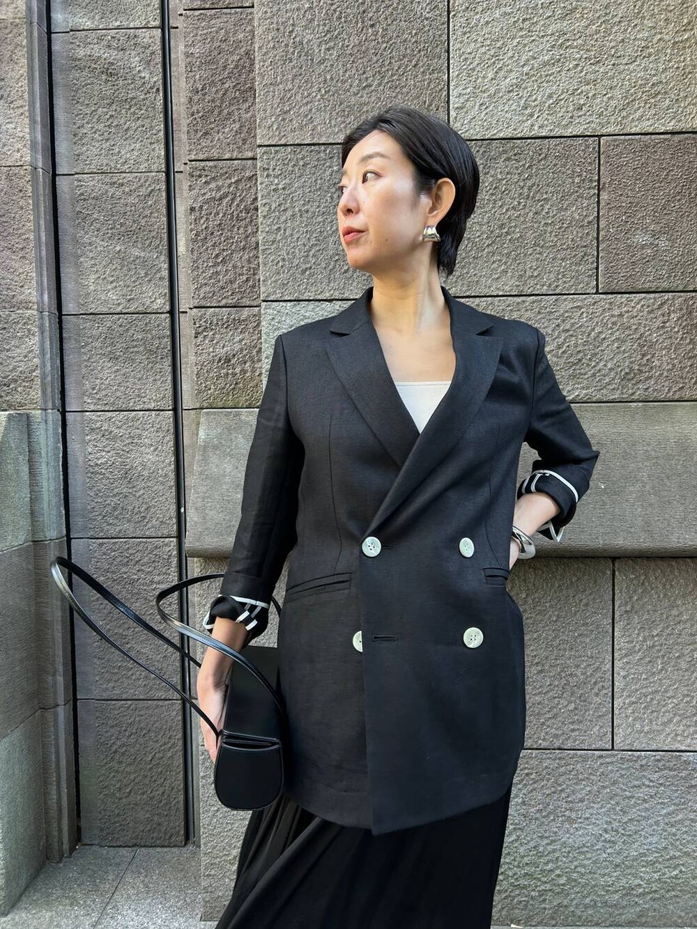 ベージュ系のタンクトップ、ブラック系のサンダル、ブラック系のテーラードジャケットを着用したレディースの冬コーディネートの5枚目の写真