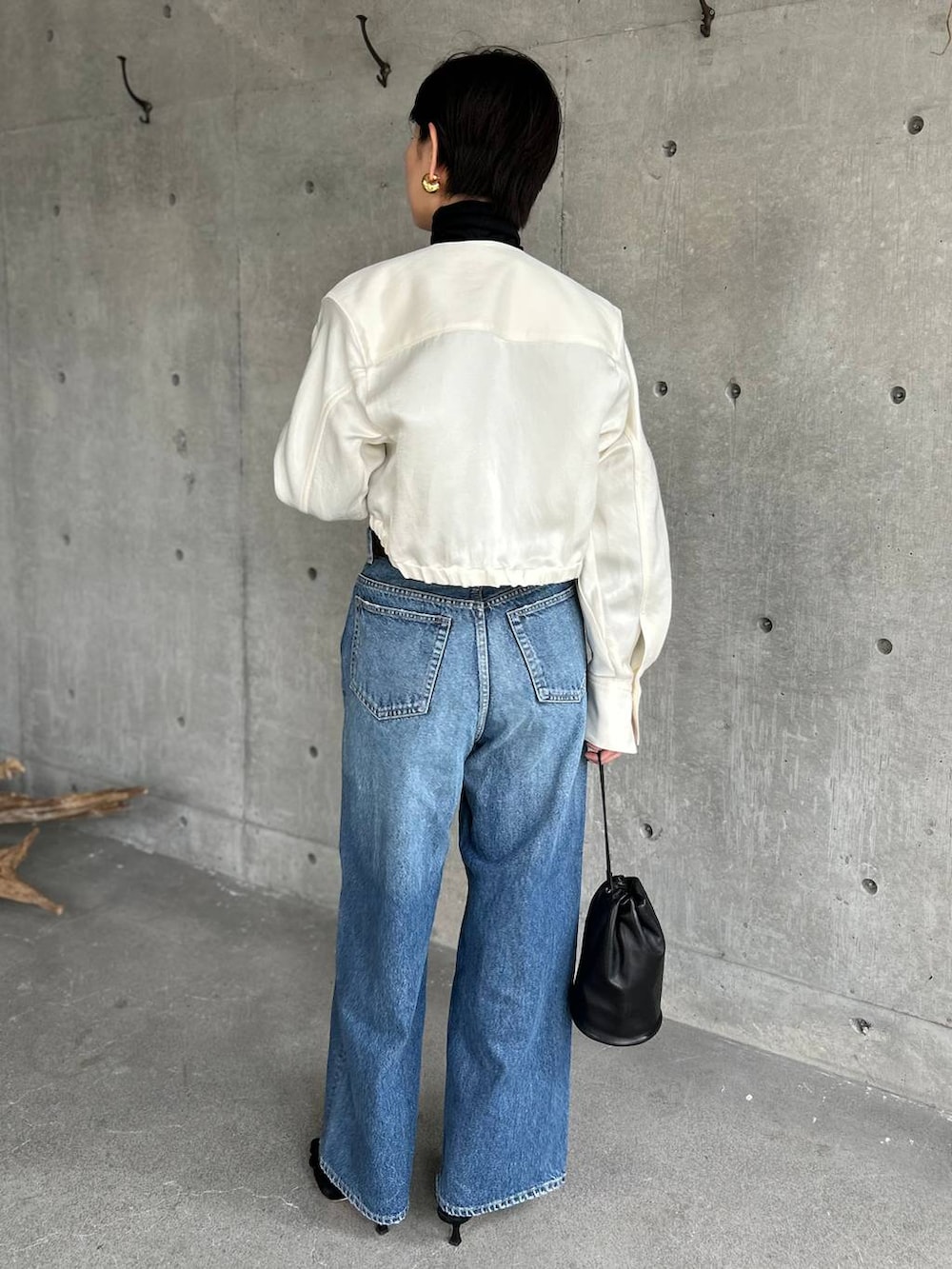 ブラック系のニット/セーター、ブルー系のデニムパンツ、ホワイト系のシャツ/ブラウスを着用したレディースの冬コーディネートの5枚目の写真