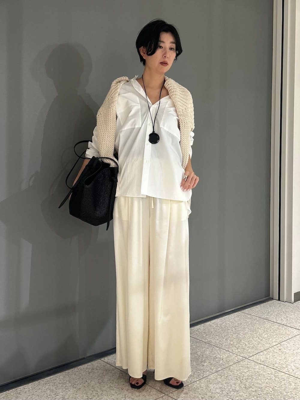 ホワイト系のニット/セーター、ホワイト系のシャツ/ブラウス、ブラック系のトレンチコートを着用したレディースの冬コーディネートの7枚目の写真