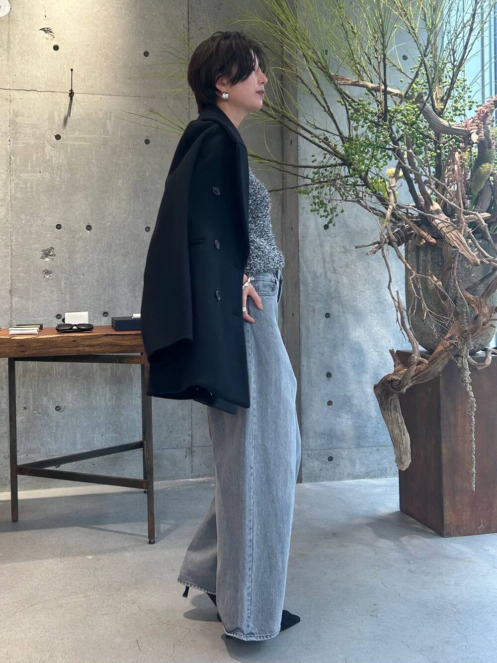 グレー系のデニムパンツ、ブラック系のピーコート、シルバー系のニット/セーターを着用したレディースの秋コーディネートの3枚目の写真