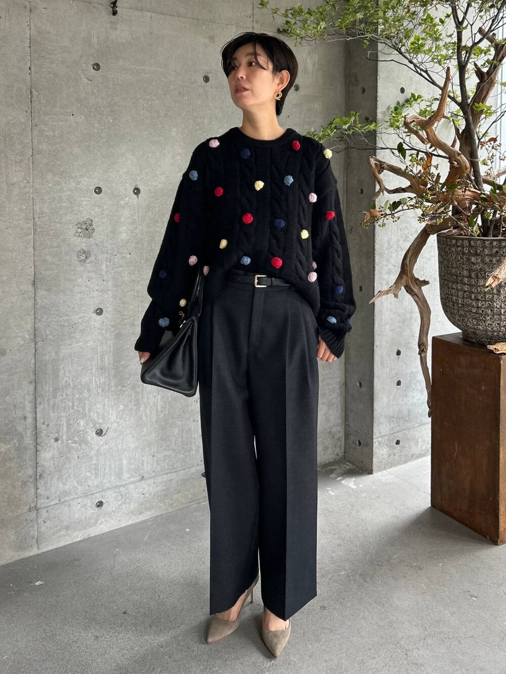 グレー系のスラックス、ブラック系のニット/セーター、ブラウン系のベルトを着用したレディースの秋コーディネートの2枚目の写真