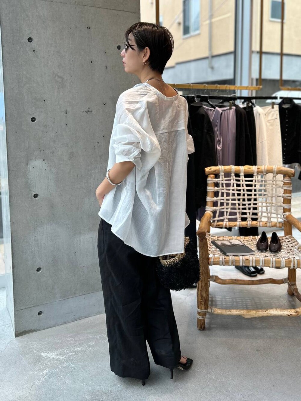 ブラック系のタンクトップ、ブラック系のかごバッグ、ブラック系のスラックスを着用したレディースの夏コーディネートの5枚目の写真