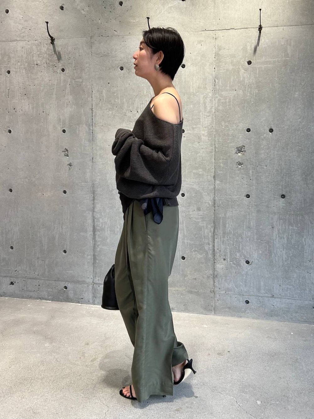 ブラック系のチューブトップ、グリーン系のニット/セーター、グリーン系のスラックスを着用したレディースの春コーディネートの4枚目の写真