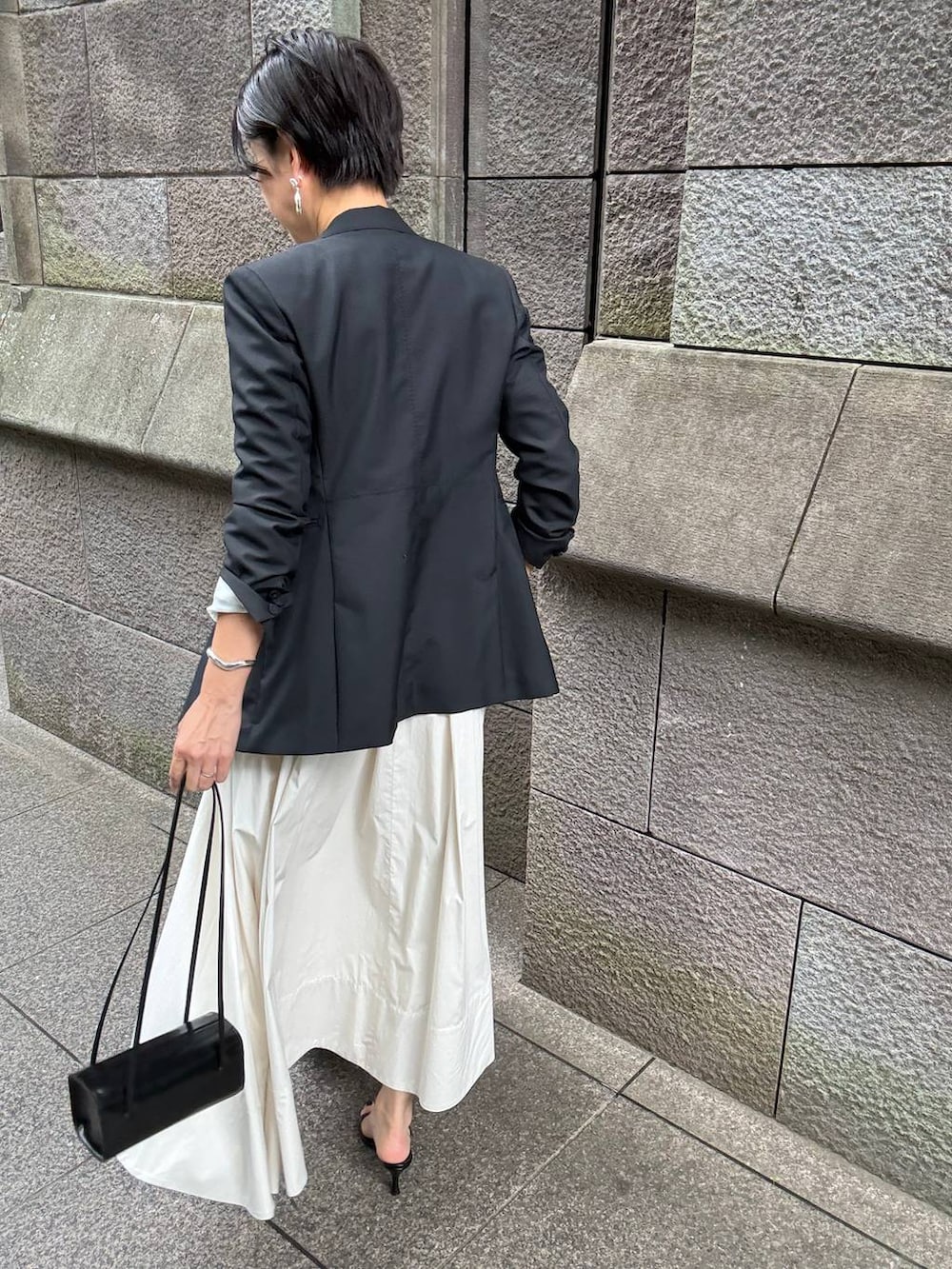 ベージュ系のスカート、ホワイト系のTシャツ/カットソー、ブラック系のテーラードジャケットを着用したレディースの夏コーディネートの7枚目の写真