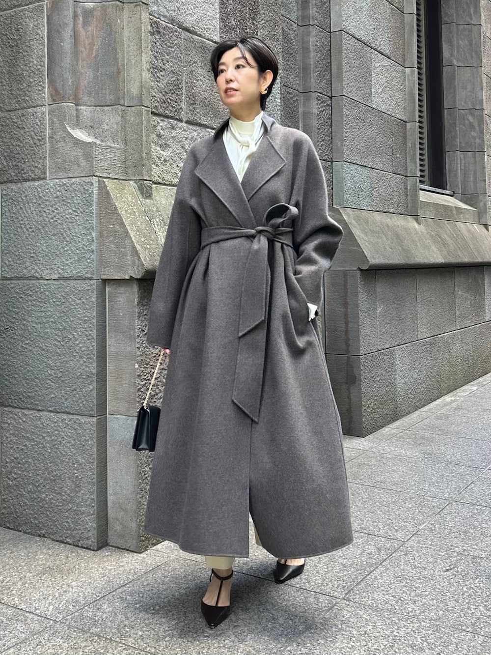 ブラウン系のノーカラーコート、ホワイト系のスラックス、ホワイト系のシャツ/ブラウスを着用したレディースの秋コーディネートの5枚目の写真