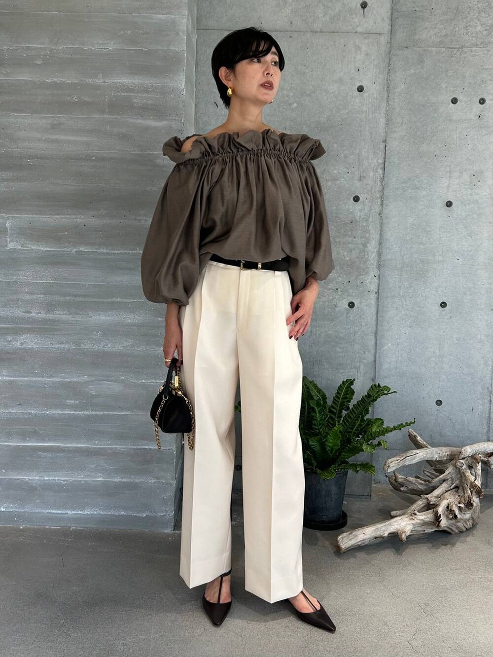 ホワイト系のスラックス、ブラウン系のトレンチコート、ブラウン系のその他アウターを着用したレディースの秋コーディネートの3枚目の写真