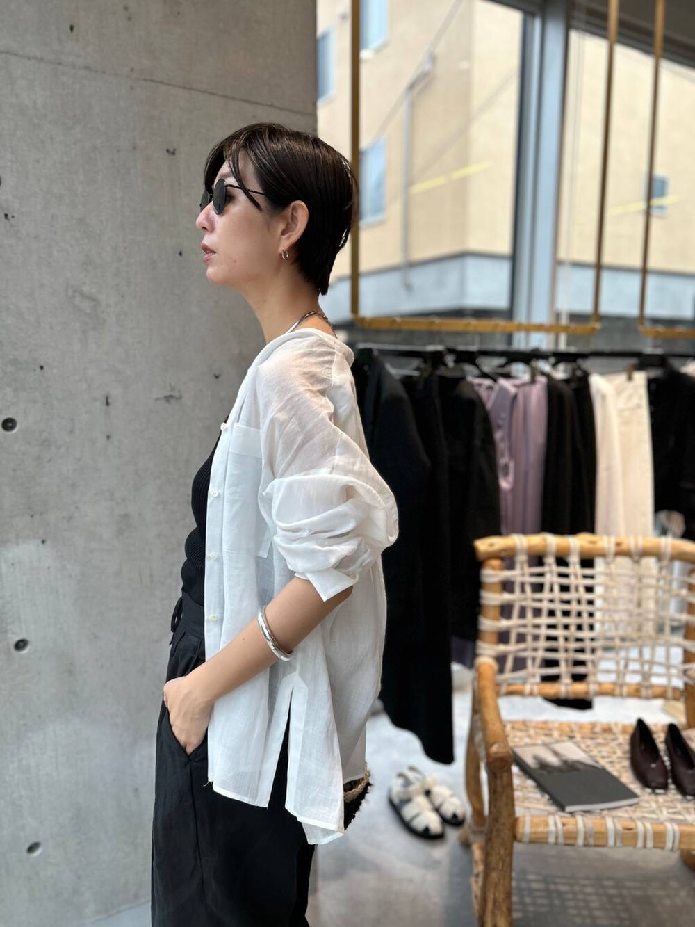 ブラック系のタンクトップ、ブラック系のかごバッグ、ブラック系のスラックスを着用したレディースの夏コーディネートの6枚目の写真