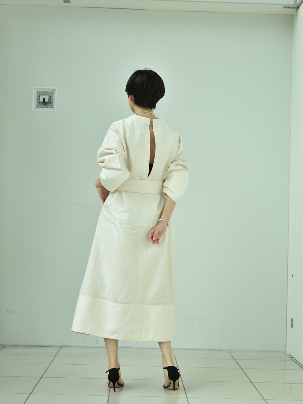 ホワイト系のワンピース、ブラック系のサンダル、シルバー系のネックレスを着用したレディースの春コーディネートの3枚目の写真