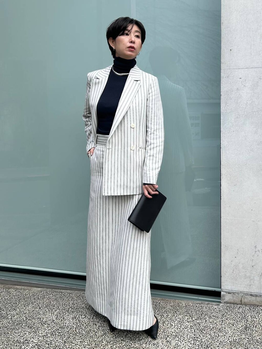 ブルー系のニット/セーター、ホワイト系のテーラードジャケット、ホワイト系のスカートを着用したレディースの冬コーディネートの2枚目の写真