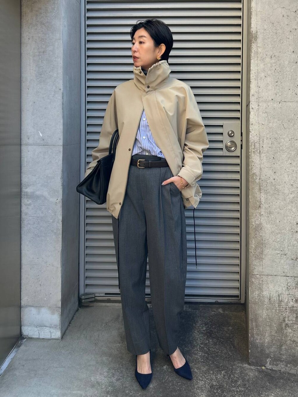 グレー系のニット/セーター、ブルー系のシャツ/ブラウス、グレー系のスラックスを着用したレディースの冬コーディネートの2枚目の写真