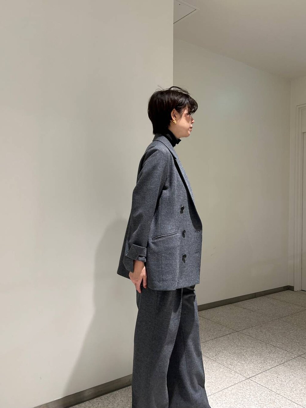 ブラック系のニット/セーター、ブラック系のトレンチコート、グレー系のスラックスを着用したレディースの秋コーディネートの7枚目の写真