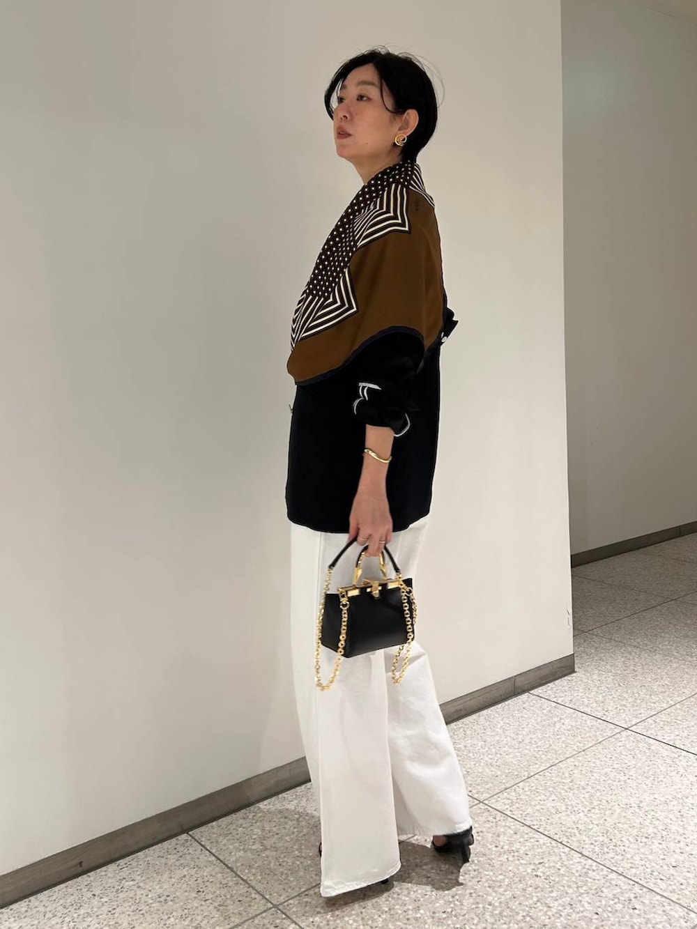 ホワイト系のデニムパンツ、ホワイト系のタンクトップ、ブラック系のテーラードジャケットを着用したレディースの春コーディネートの3枚目の写真