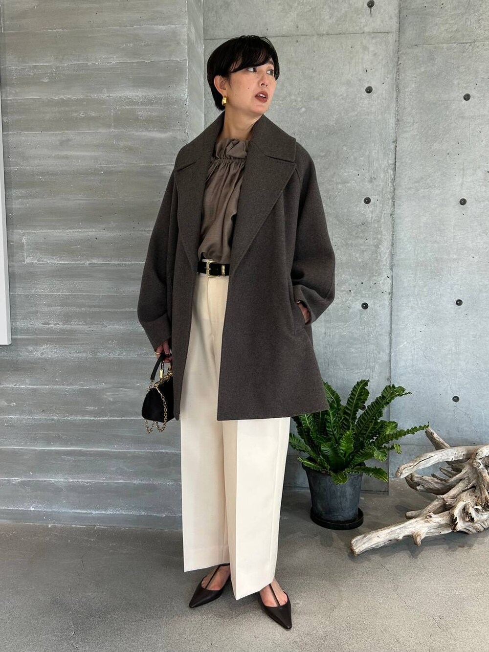 ホワイト系のスラックス、ブラウン系のトレンチコート、ブラウン系のその他アウターを着用したレディースの秋コーディネートの8枚目の写真