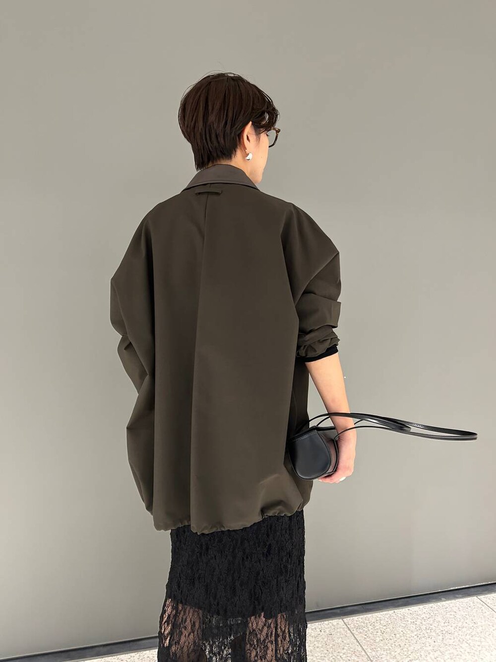 ブラック系のTシャツ/カットソー、ブラウン系のステンカラーコート、ブラック系のスカートを着用したレディースの夏コーディネートの8枚目の写真