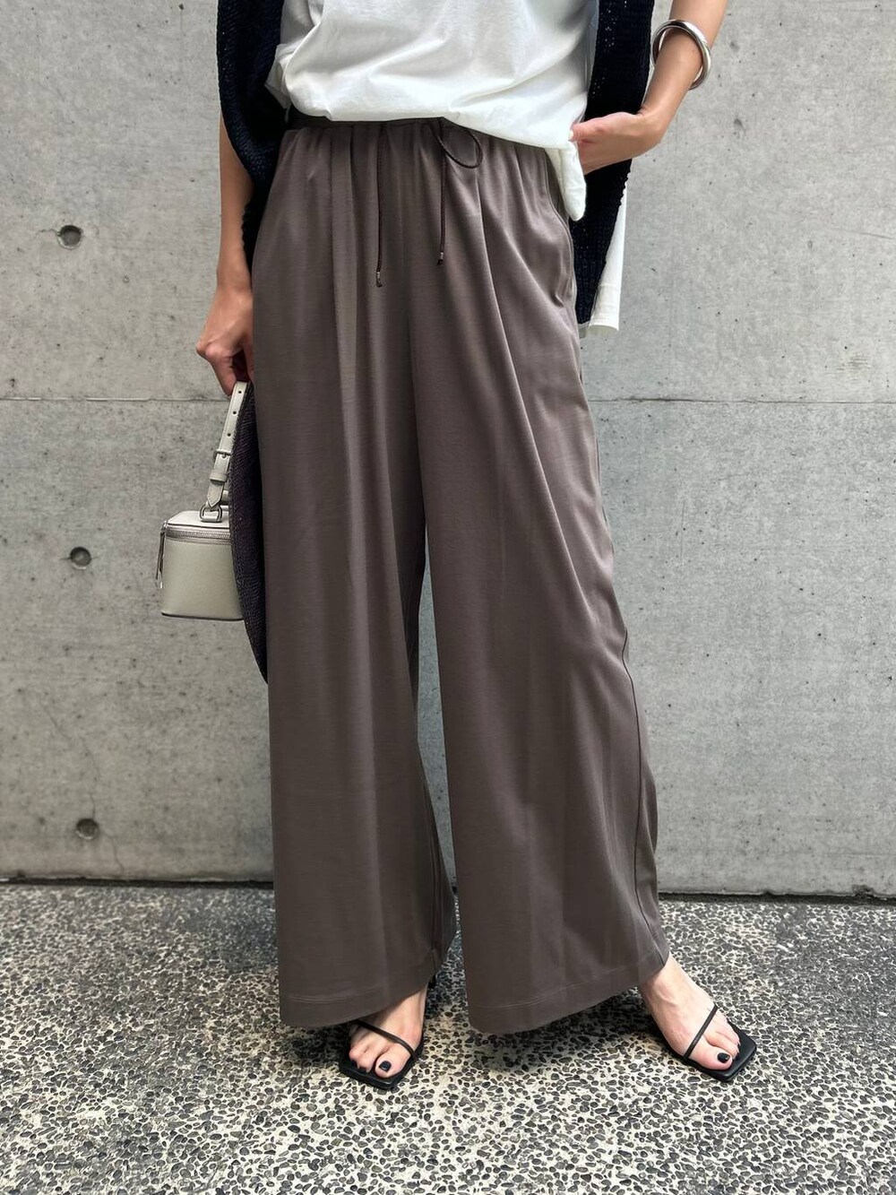 ホワイト系のTシャツ/カットソー、ブラック系のアンサンブル、ブラック系のサンダルを着用したレディースの春コーディネートの7枚目の写真