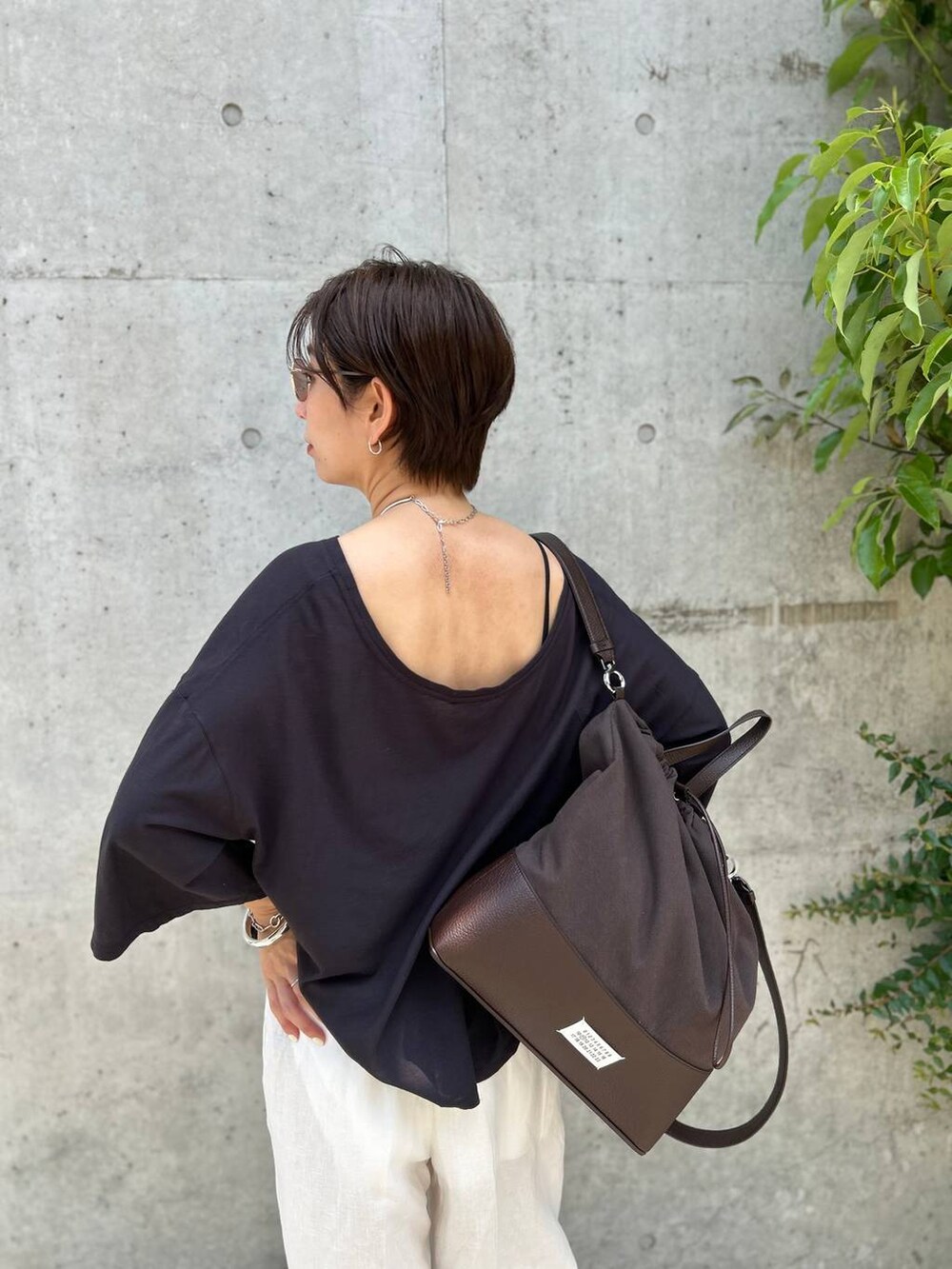 ブラック系のチューブトップ、ホワイト系のスラックス、グレー系のTシャツ/カットソーを着用したレディースの春コーディネートの6枚目の写真