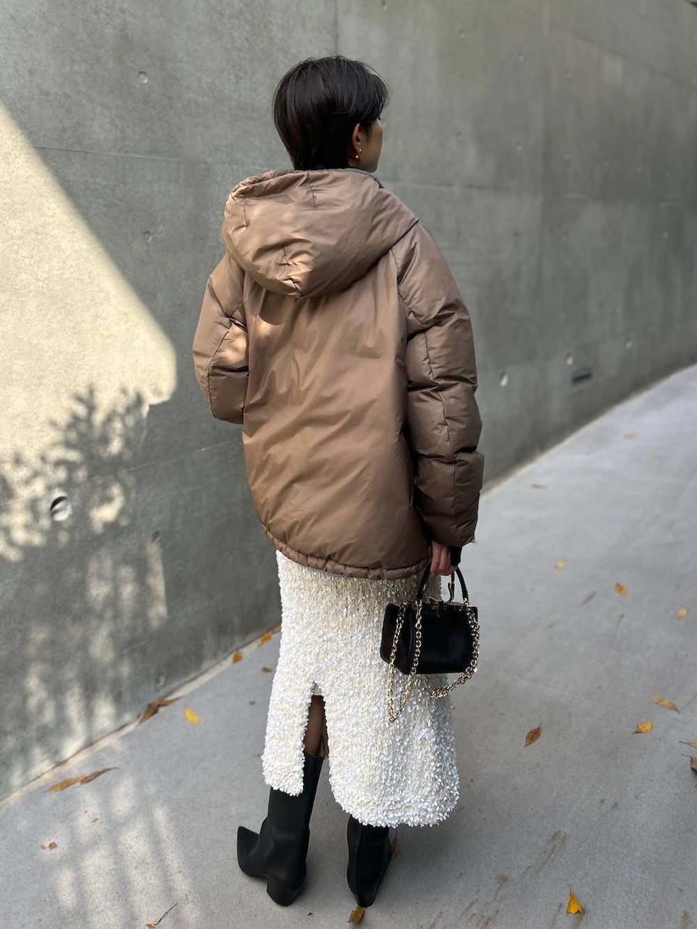 ブラック系のニット/セーター、ブルー系のシャツ/ブラウス、ブラウン系のダウンジャケット/コートを着用したレディースの冬コーディネートの5枚目の写真