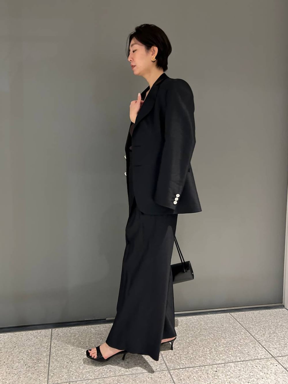 ブラック系のスラックス、ブラック系のテーラードジャケットを着用したレディースの春コーディネートの3枚目の写真
