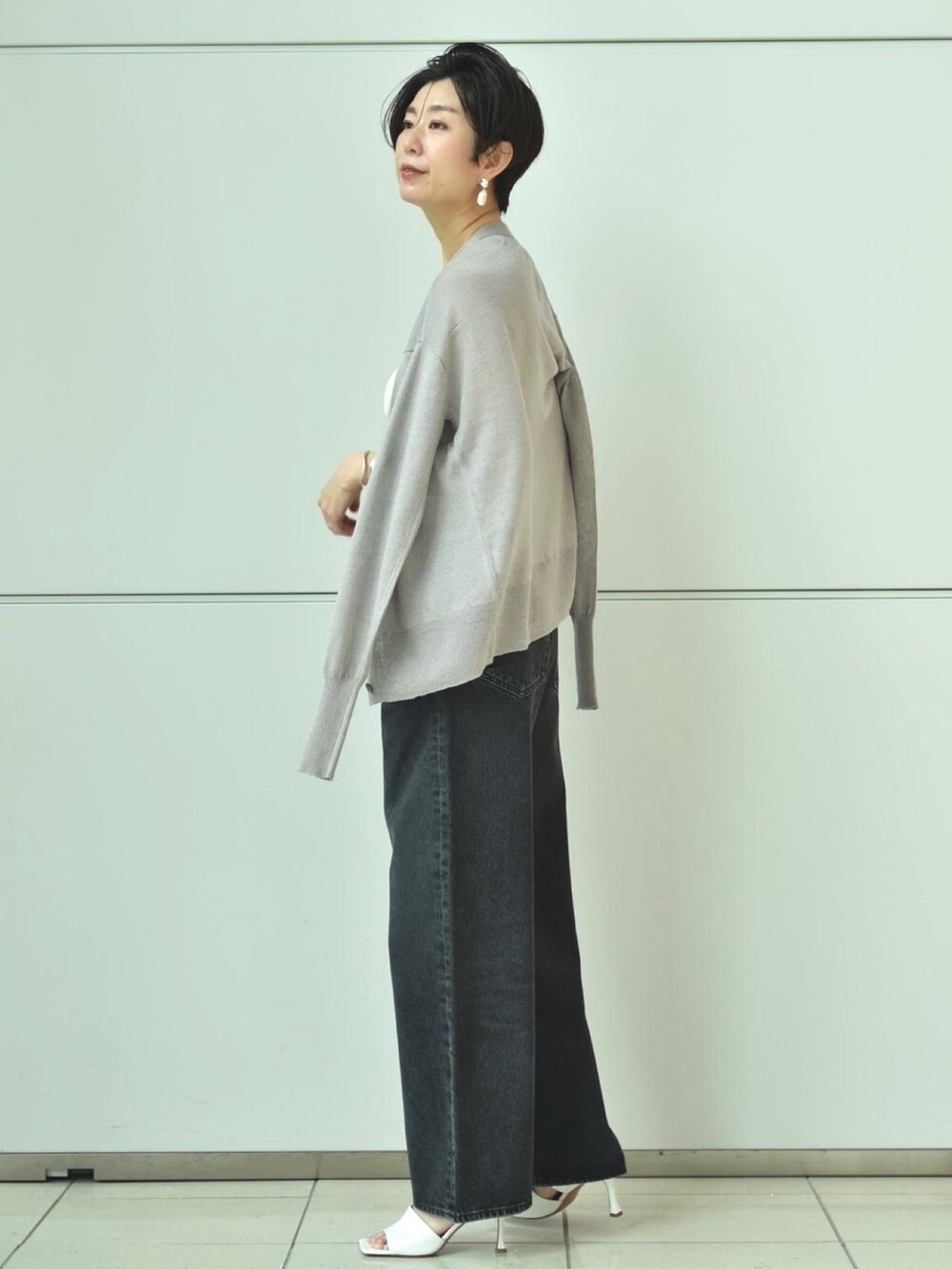 グレー系のカーディガン/ボレロ、ホワイト系のタンクトップ、グレー系のデニムパンツを着用したレディースの春コーディネートの3枚目の写真