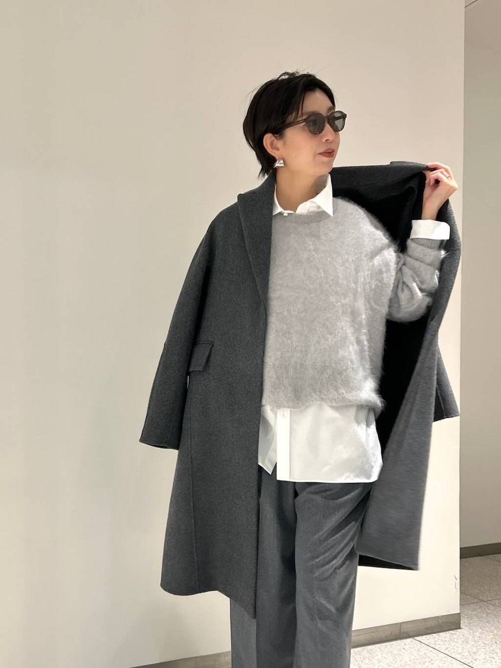 グレー系のニット/セーター、ホワイト系のシャツ/ブラウス、グレー系のスラックスを着用したレディースの秋コーディネートの5枚目の写真