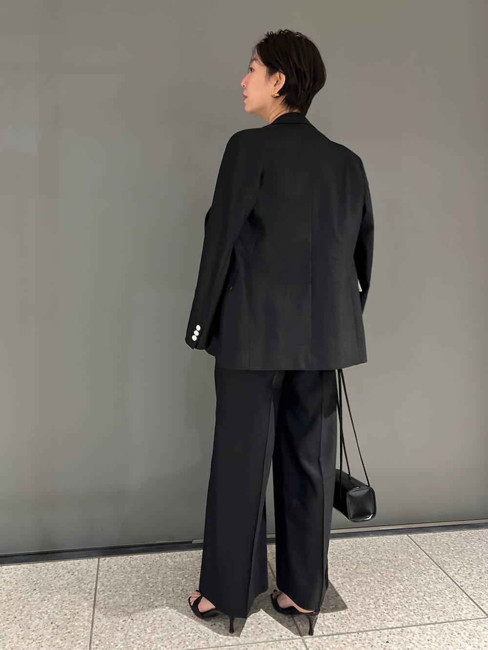 ブラック系のスラックス、ブラック系のテーラードジャケットを着用したレディースの春コーディネートの4枚目の写真