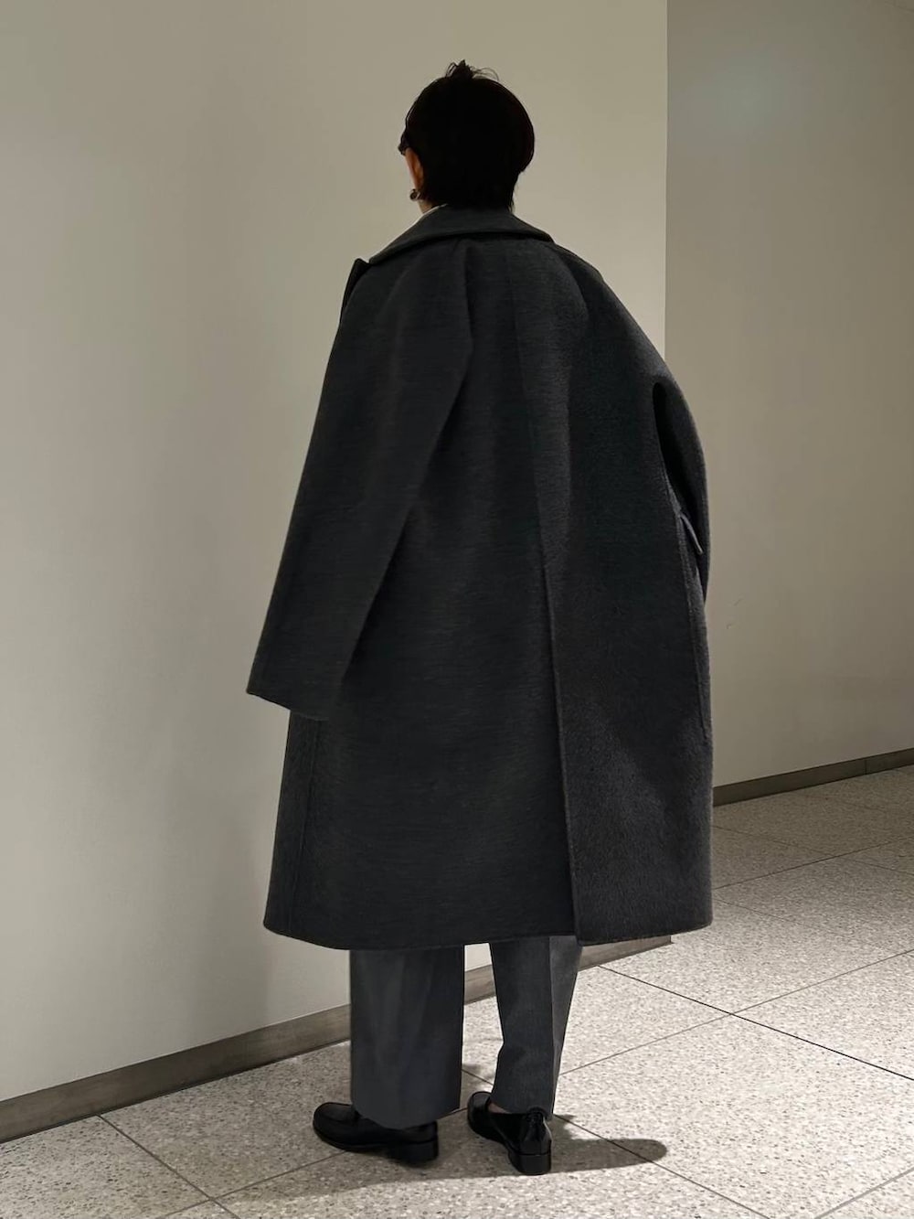 グレー系のニット/セーター、ホワイト系のシャツ/ブラウス、グレー系のスラックスを着用したレディースの秋コーディネートの4枚目の写真