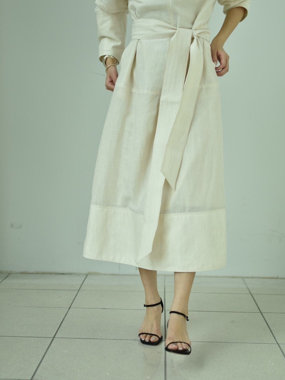 ホワイト系のワンピース、ブラック系のサンダル、シルバー系のネックレスを着用したレディースの春コーディネートの4枚目の写真