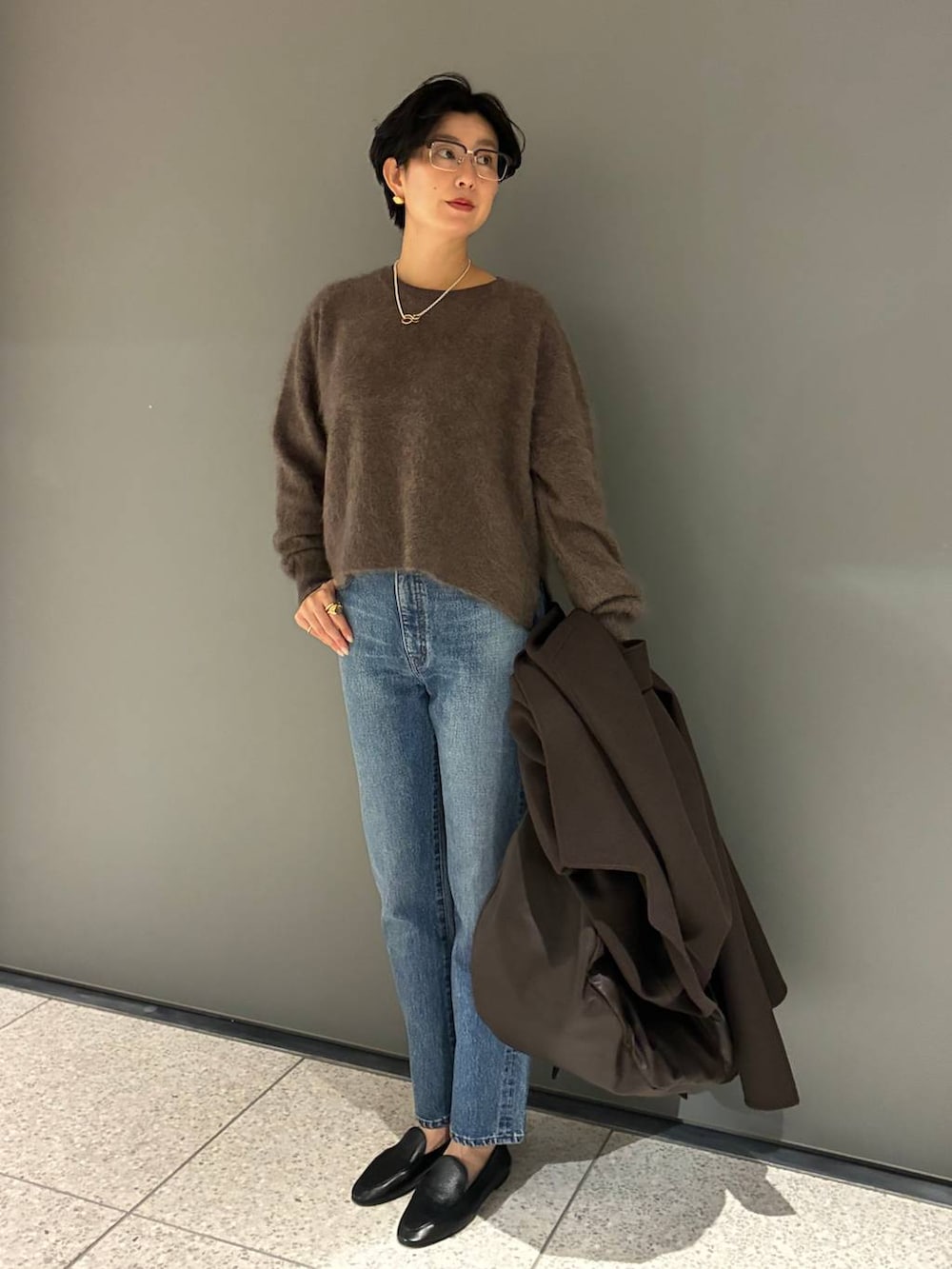 ブルー系のデニムパンツ、ブラウン系のニット/セーター、ブラウン系のノーカラーコートを着用したレディースの秋コーディネートの4枚目の写真