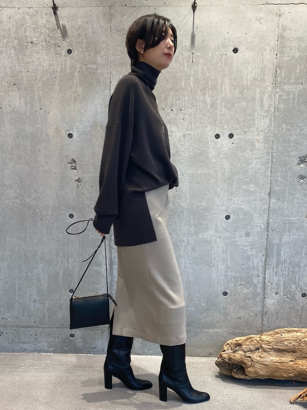 ブラウン系のニット/セーター、ベージュ系のスカート、ブラック系のブーツを着用したレディースの秋コーディネートの2枚目の写真