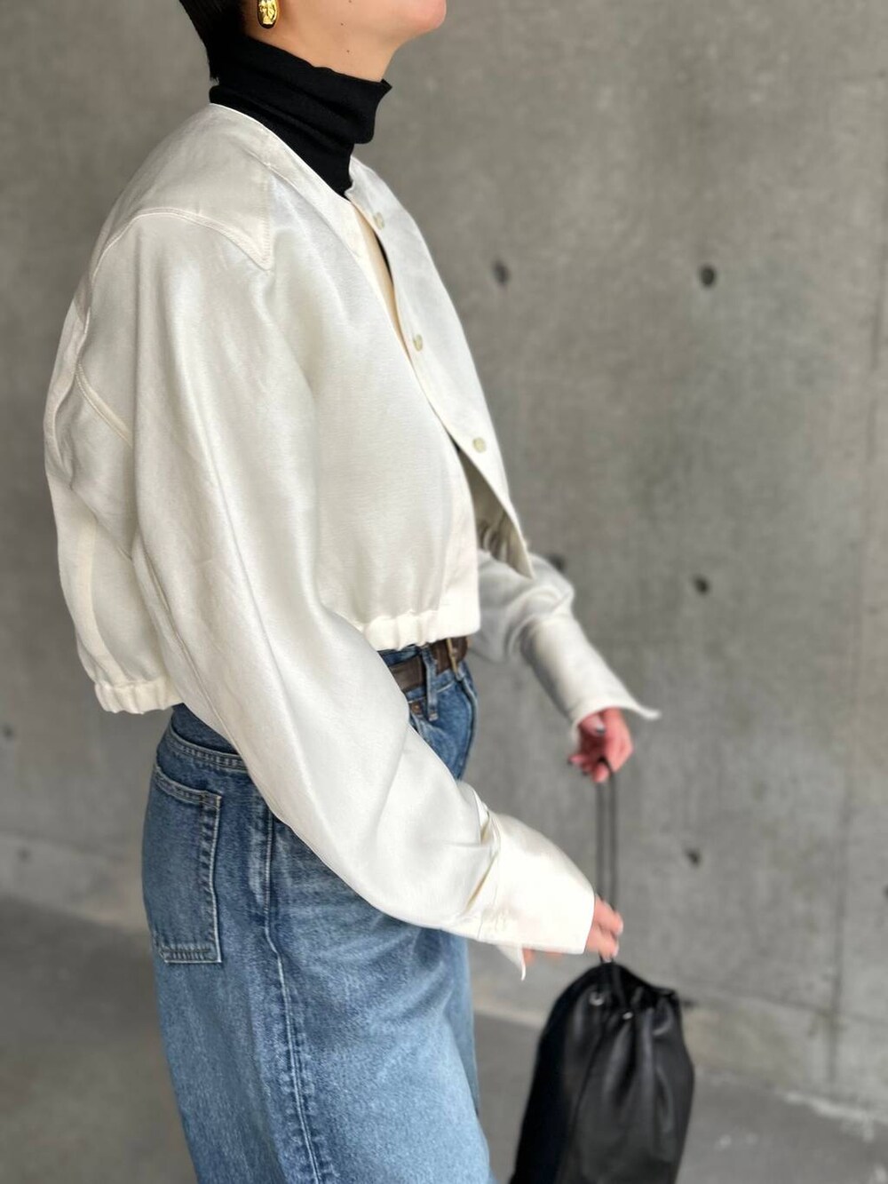 ブラック系のニット/セーター、ブルー系のデニムパンツ、ホワイト系のシャツ/ブラウスを着用したレディースの冬コーディネートの7枚目の写真