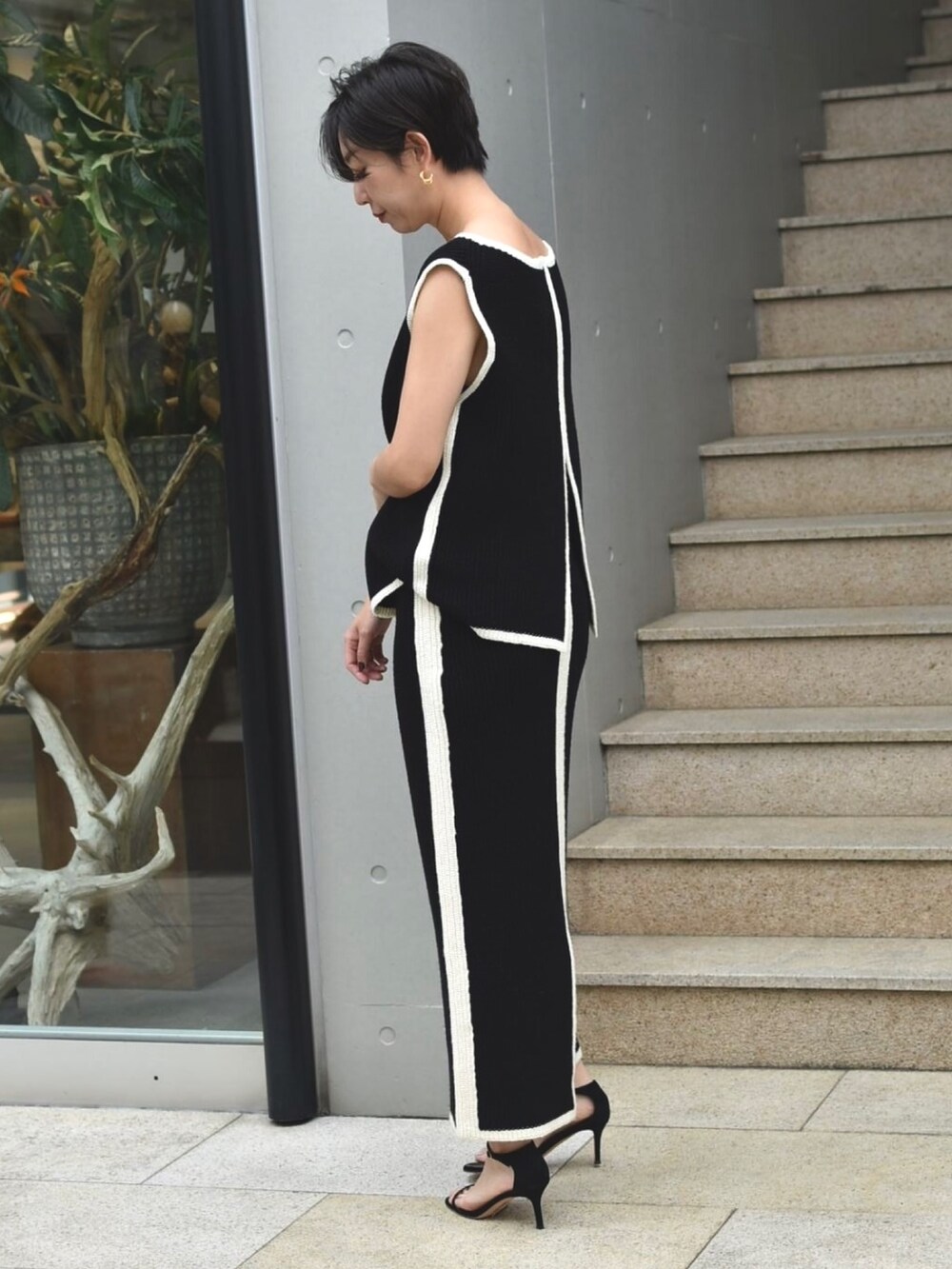 ブラック系のニット/セーター、ブラック系のスカート、ブラック系のサンダルを着用したレディースの夏コーディネートの2枚目の写真