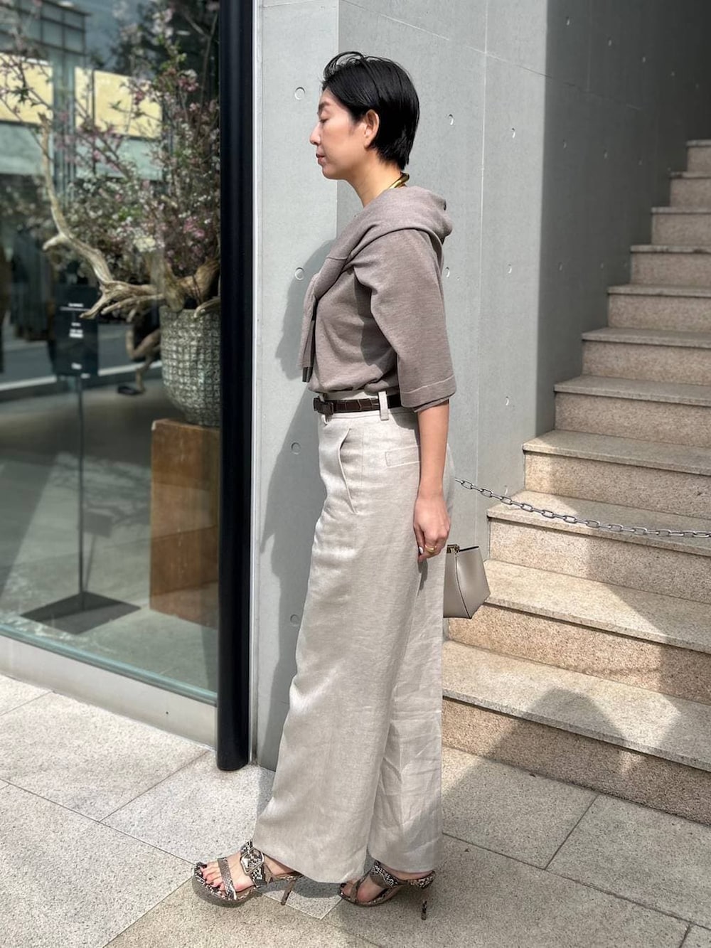 ホワイト系のスラックス、ブラウン系のニット/セーター、ブラウン系のカーディガン/ボレロを着用したレディースの春コーディネートの3枚目の写真