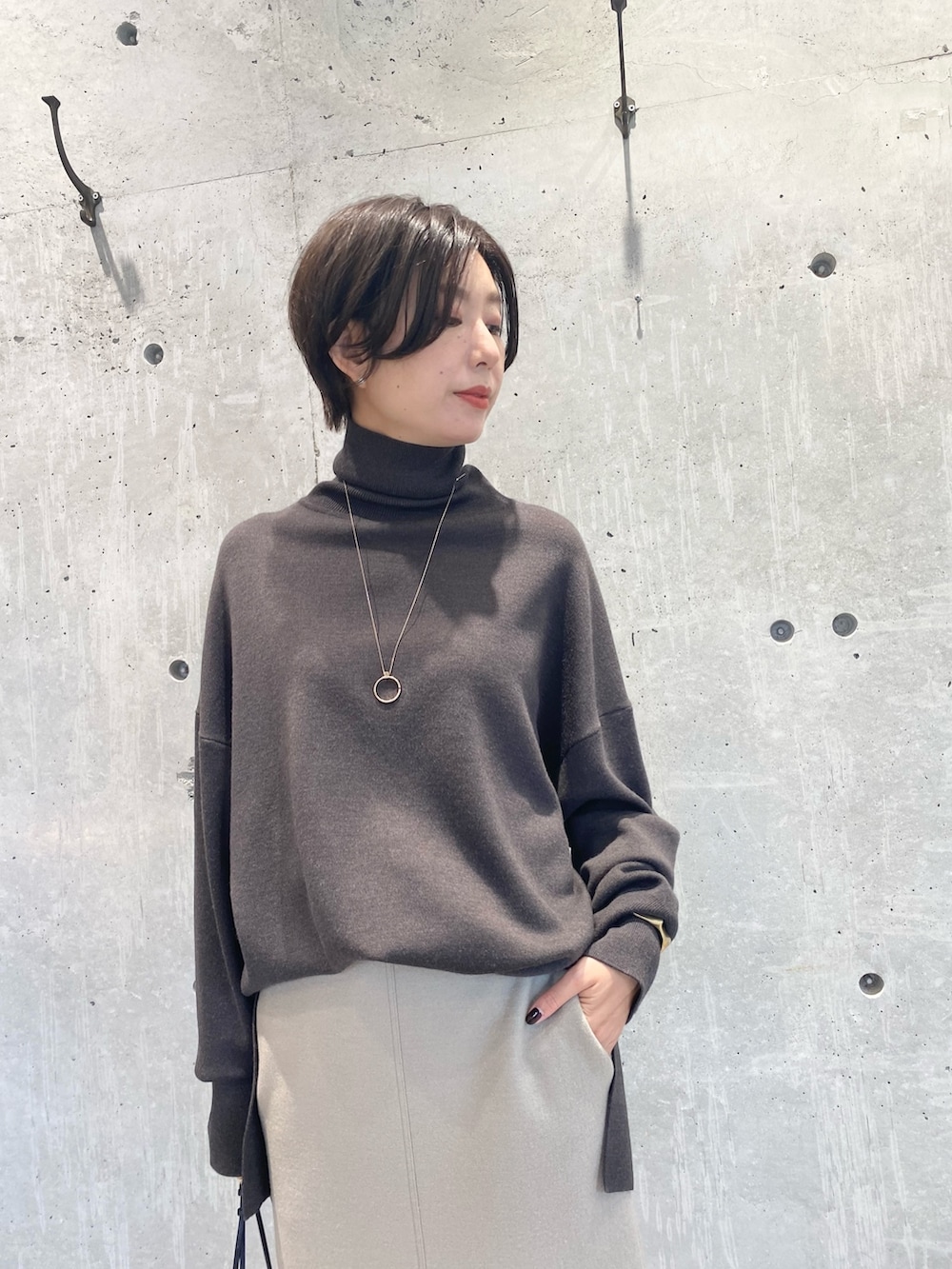 ブラウン系のニット/セーター、ベージュ系のスカート、ブラック系のブーツを着用したレディースの秋コーディネートの4枚目の写真