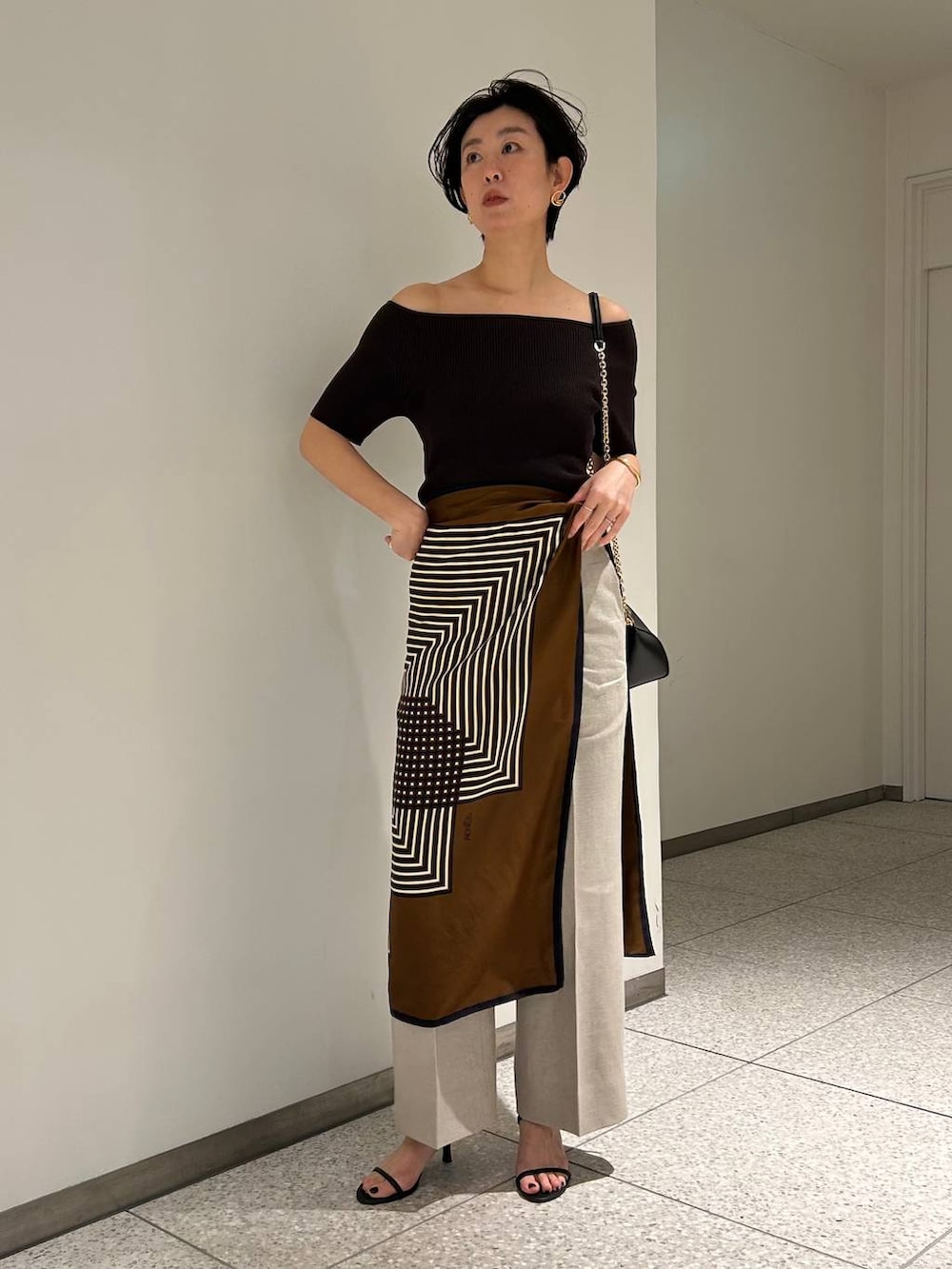 ホワイト系のスラックス、ブラウン系のTシャツ/カットソー、ブラウン系のバンダナ/スカーフを着用したレディースの春コーディネートの2枚目の写真