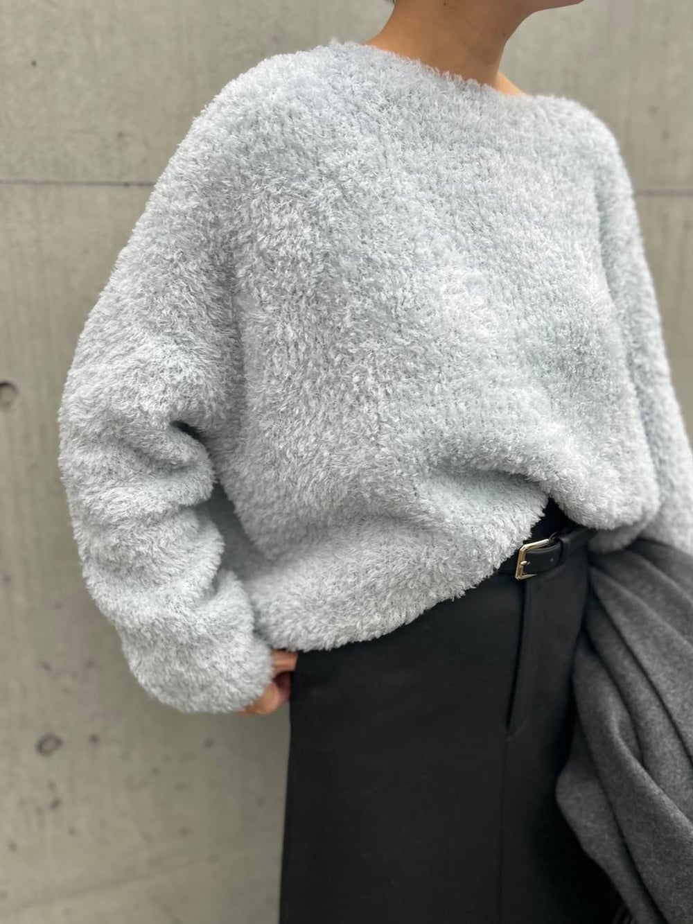 ブルー系のニット/セーター、グレー系のチェスターコート、ブラック系のスカートを着用したレディースの秋コーディネートの7枚目の写真