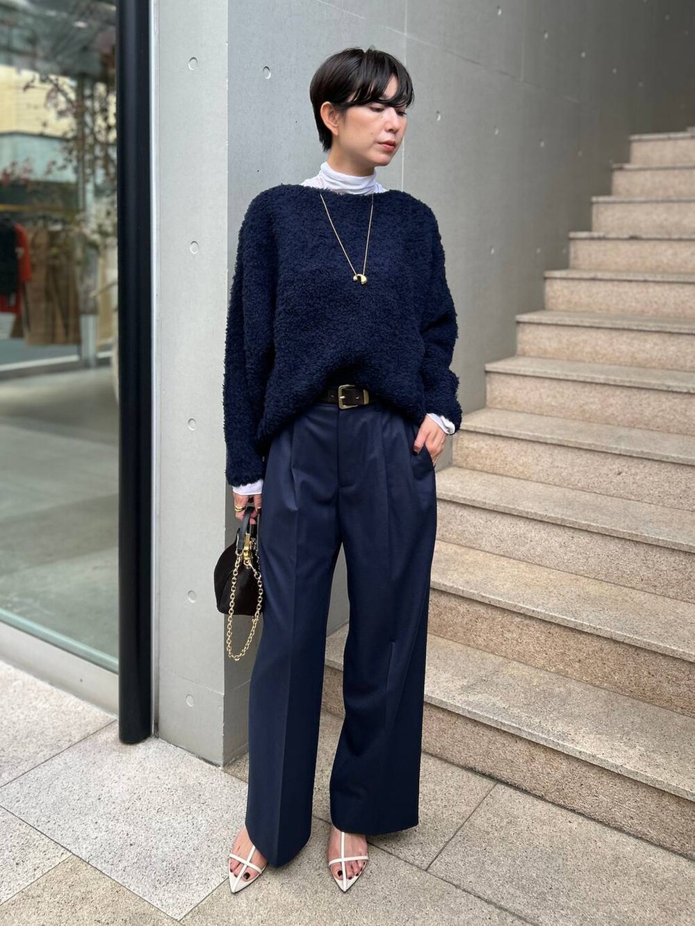 ブルー系のニット/セーター、ホワイト系のその他トップス、ブルー系のスラックスを着用したレディースの秋コーディネートの2枚目の写真