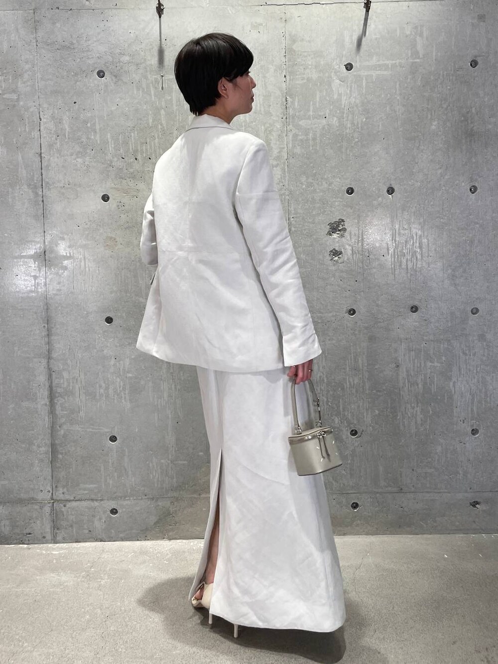 ホワイト系のタンクトップ、グレー系のベスト、ベージュ系のサンダルを着用したレディースの春コーディネートの4枚目の写真