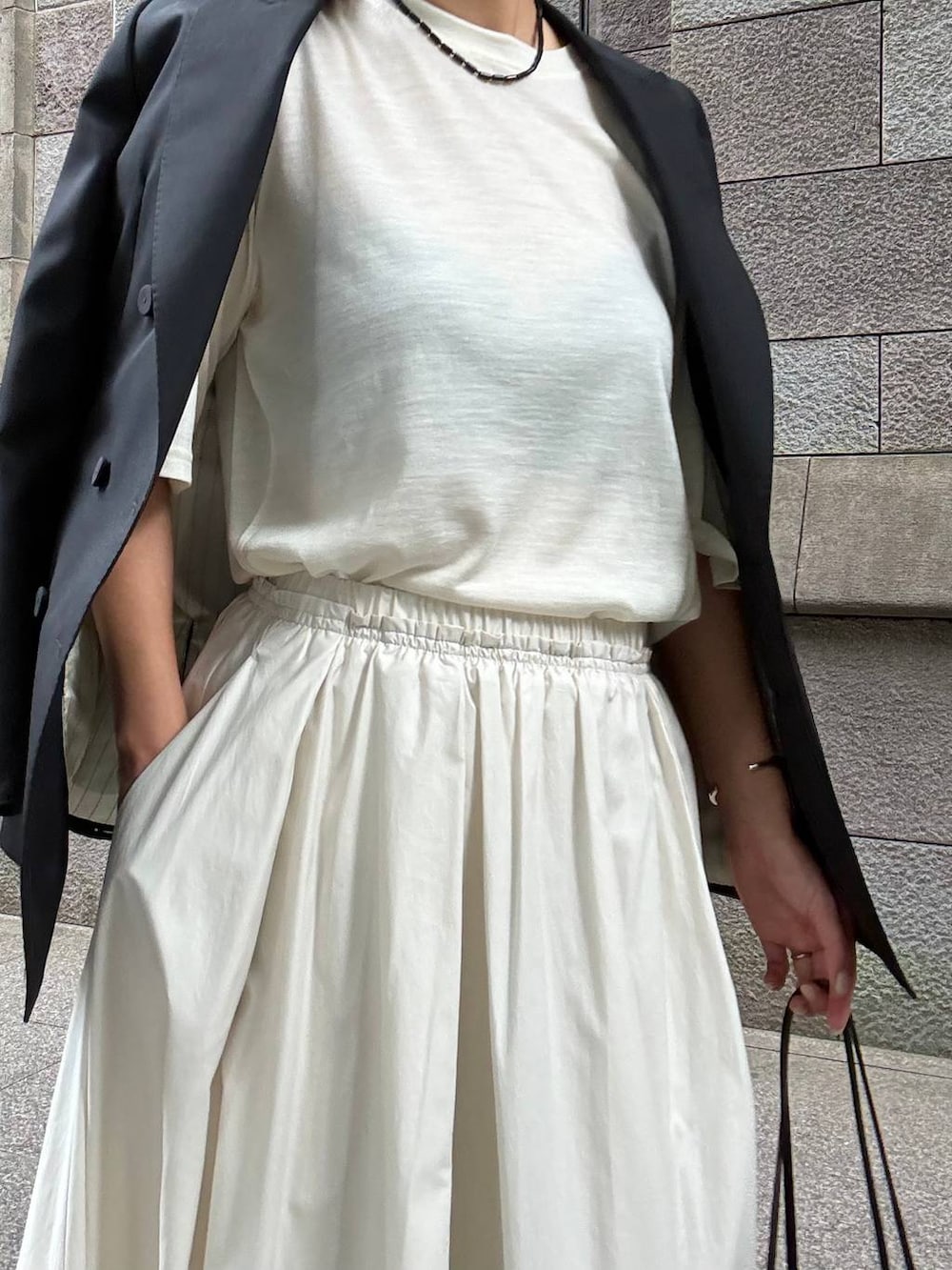 ベージュ系のスカート、ホワイト系のTシャツ/カットソー、ブラック系のテーラードジャケットを着用したレディースの夏コーディネートの9枚目の写真