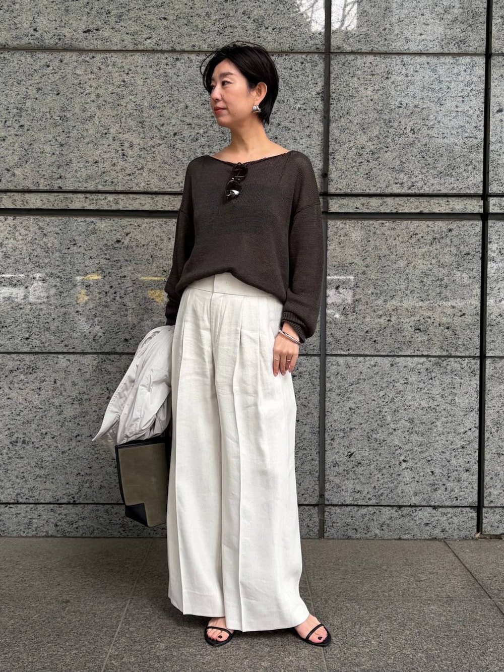 グリーン系のニット/セーター、ホワイト系のスラックス、グレー系のナイロンジャケットを着用したレディースの春コーディネートの4枚目の写真