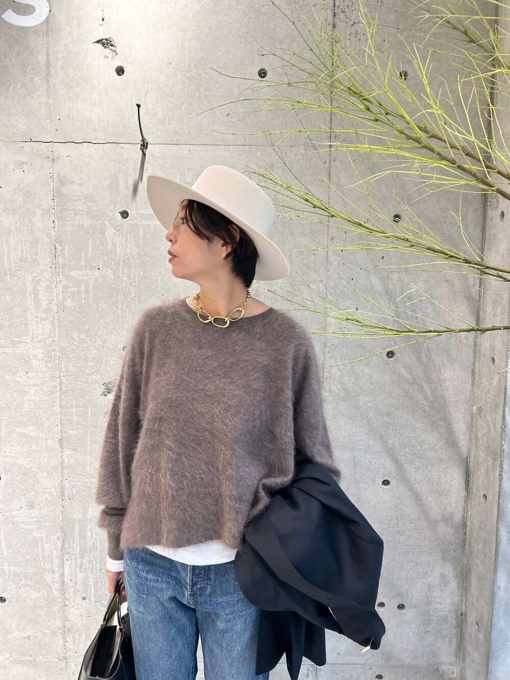 ブルー系のデニムパンツ、ブラウン系のニット/セーター、ホワイト系のTシャツ/カットソーを着用したレディースの秋コーディネートの5枚目の写真