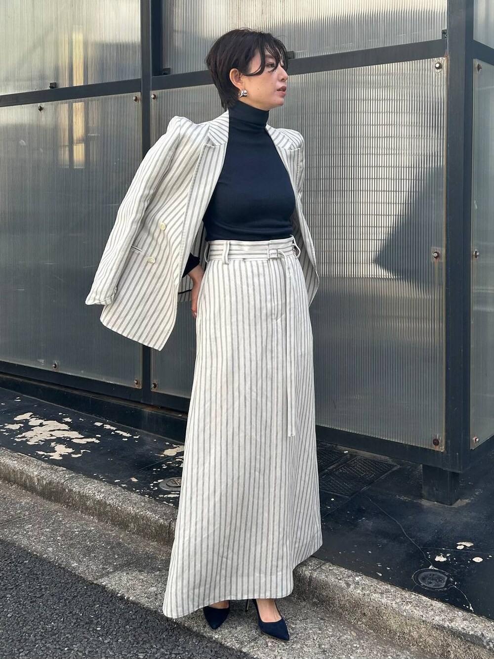 ブルー系のニット/セーター、ホワイト系のテーラードジャケット、ホワイト系のスカートを着用したレディースの冬コーディネートの2枚目の写真