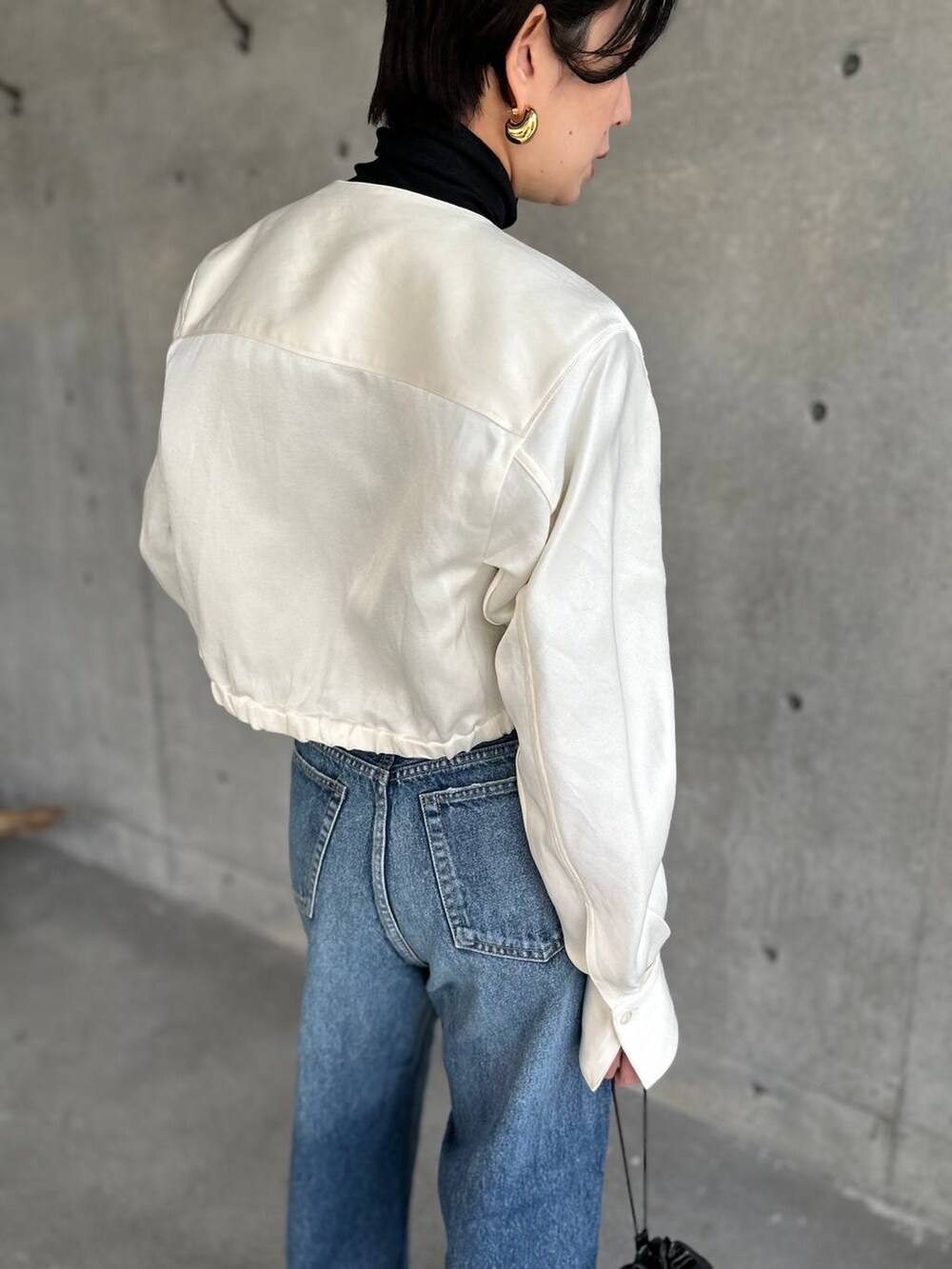 ブラック系のニット/セーター、ブルー系のデニムパンツ、ホワイト系のシャツ/ブラウスを着用したレディースの冬コーディネートの8枚目の写真