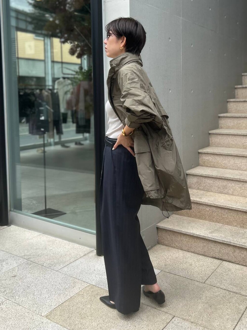 グレー系のTシャツ/カットソー、グリーン系のブルゾン、ブルー系のスラックスを着用したレディースの夏コーディネートの3枚目の写真